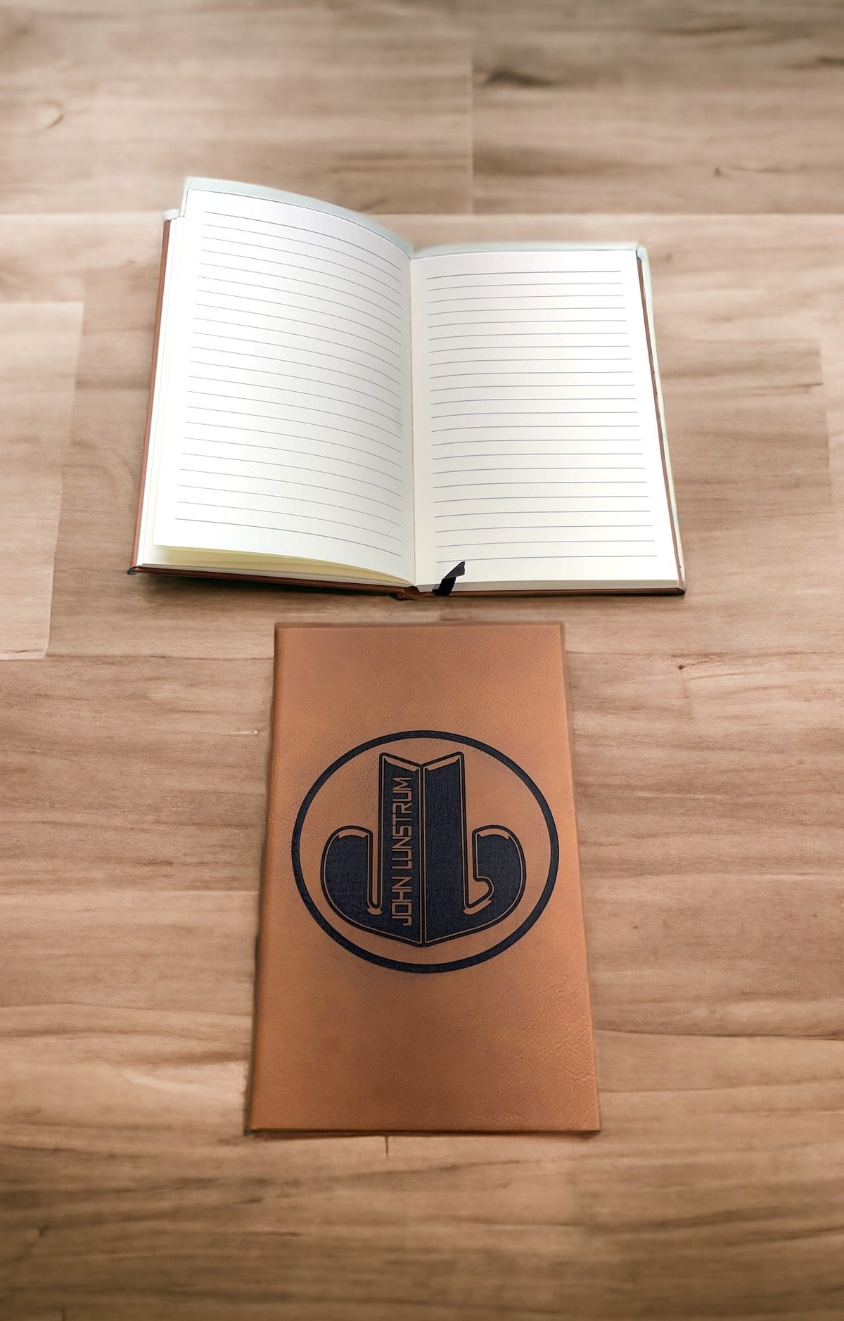 Rawhide leatherette journal with an engraved logo below an open lined journal