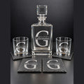 Engraved square glass decanter with stopper, two engraved rocks glasses, and engraved slate coasters